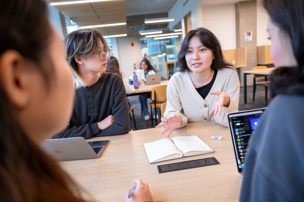 Four students at a table in Koerner Library having a discussion.