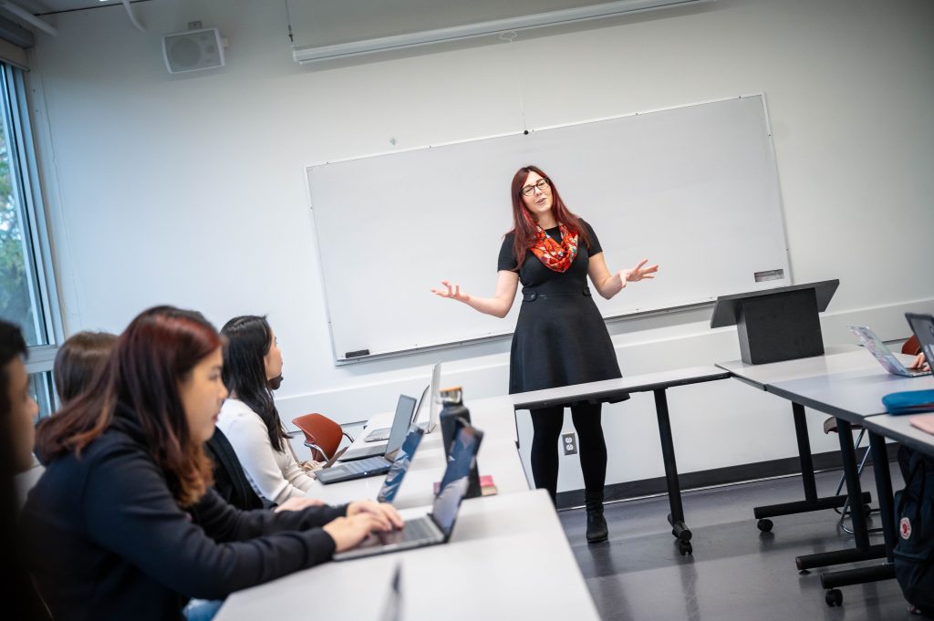 An instructor teaching a class in front of a whiteboard.